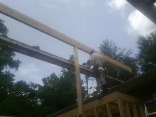 Carpenter setting a ridge beam over a new addition frame — Ice Dam Removal by Roofing Brothers in Marietta