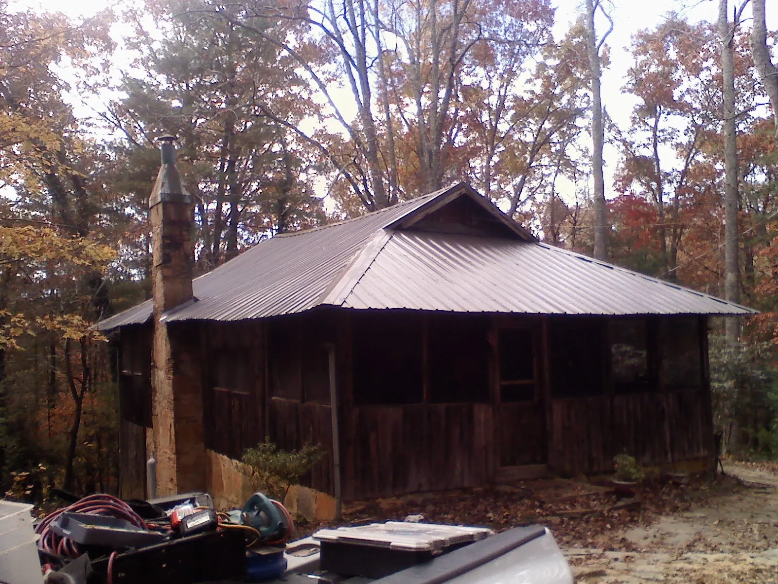 Brown metal hip roof on an old cabin with a stone chimney in Marietta