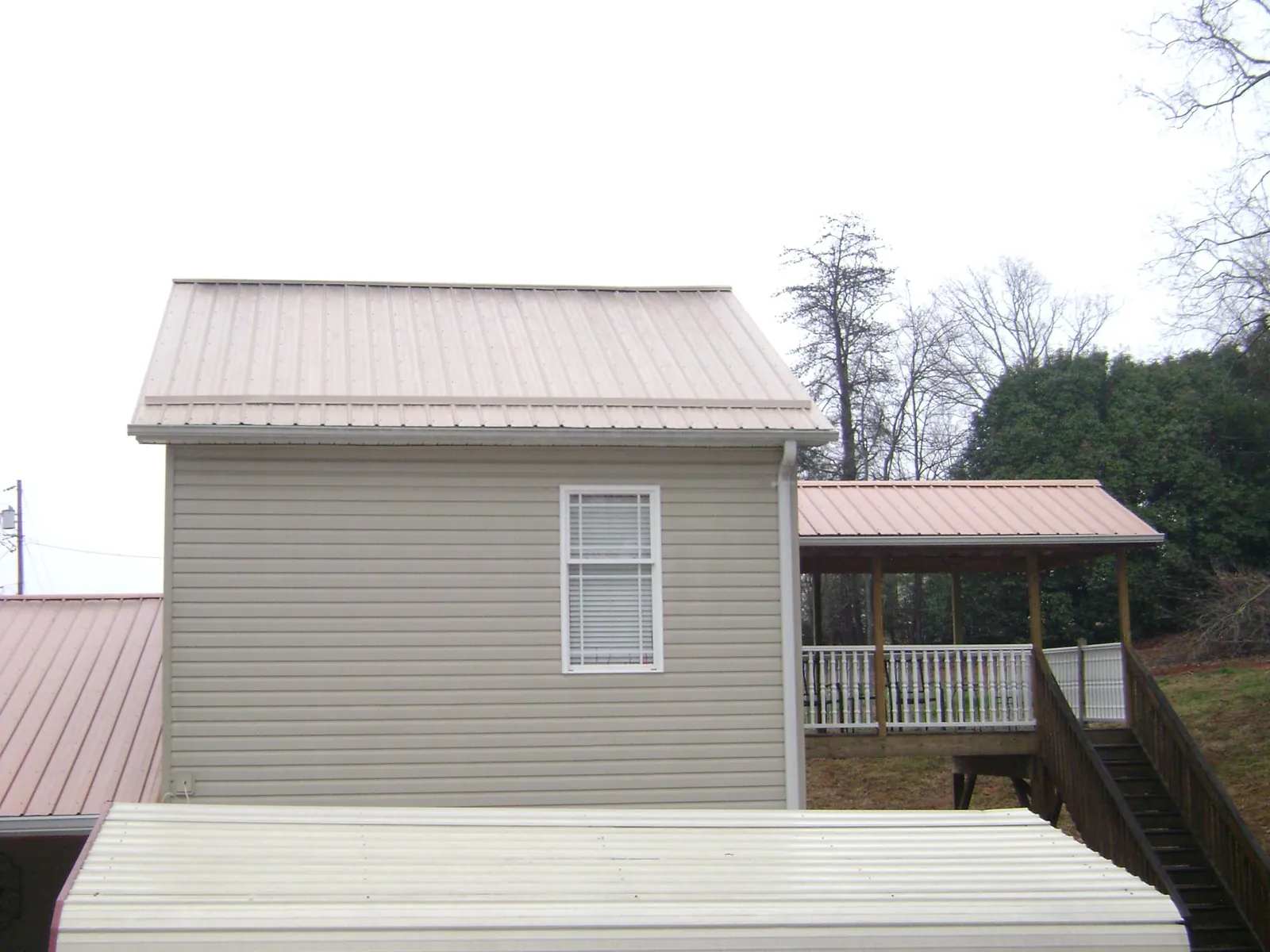 Tan metal roofs on a two story addition and attached porch, from a Roof Replacement job in Marietta